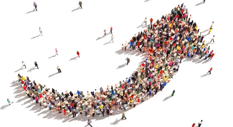 Large group of people in the shape of an arrow pointing up symbolizing direction , progress or growth
