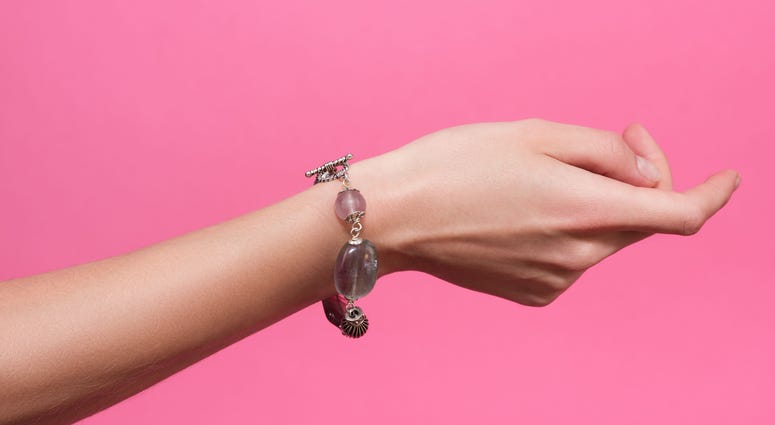 A woman's wrist on a pink background