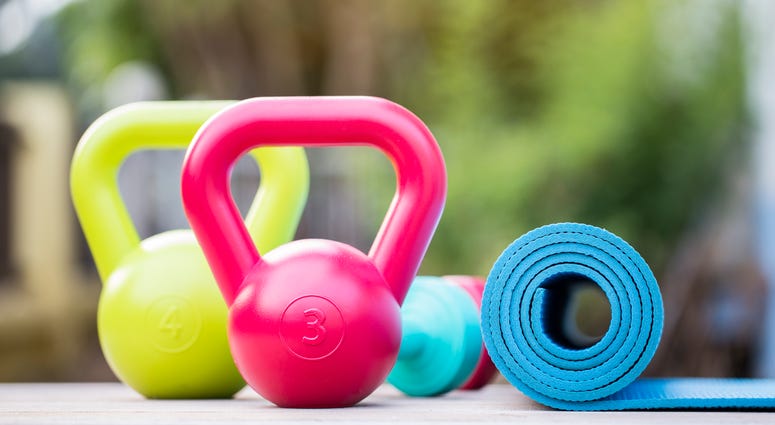 Kettlebell, dumbbell and yoga mat on wood table
