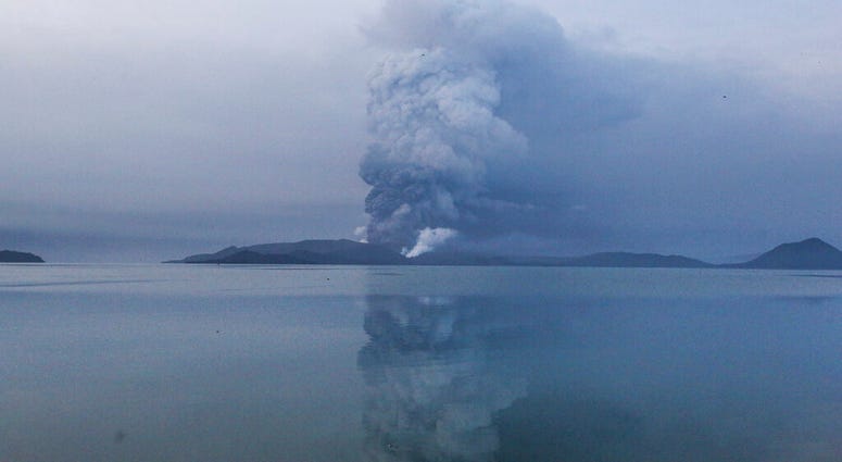 Residents wait to be evacuated as heavy ash and debris from the Taal volcano eruption continues to cover their town in Talisay, Batangas, southern Philippines on Monday, Jan. 13, 2020.