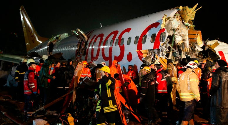 Rescue members and firefighters work around the wreckage of a plane after it skidded off the runway at Istanbul's Sabiha Gokcen Airport, in Istanbul, Wednesday, Feb. 5, 2020.