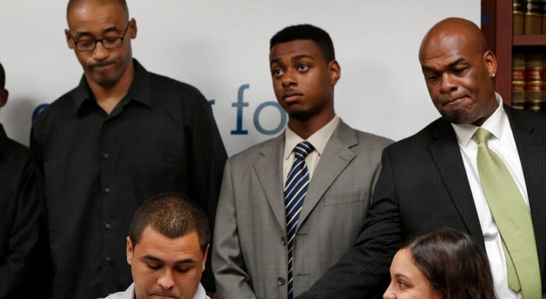 David Ourlicht, seated left, is comforted by Merault Almonar, standing at right, father of plaintiff Devin Almonar,