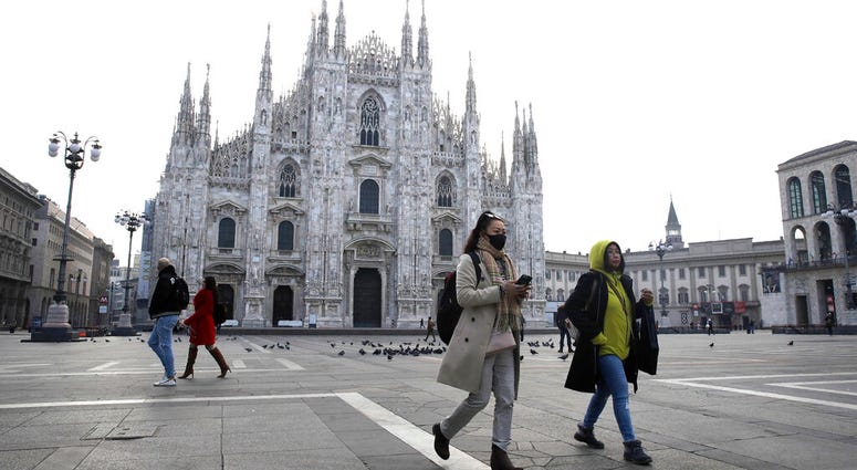 A woman wearing a sanitary mask walks past the Duomo gothic cathedral in Milan, Italy, Sunday, Feb. 23, 2020.