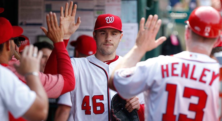 Washington Nationals flight Patrick Corbin high-fives Washington Nationals teammates in the dugout.