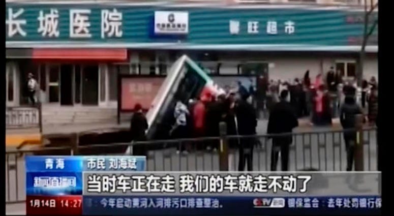 CCTV video, a bus plunges into a sinkhole in the center of a downtown street, Monday, Jan. 13, 2020, in Xining, Qinghai province, China.
