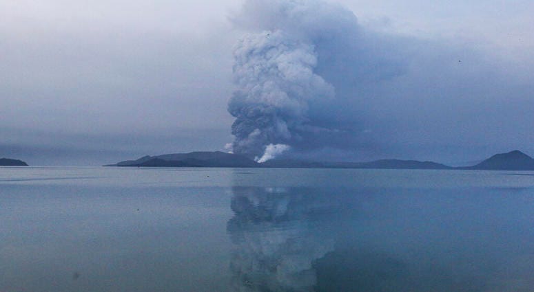 Residents wait to be evacuated as heavy ash and debris from the Taal volcano eruption continues to cover their town in Talisay, Batangas, southern Philippines on Monday, Jan. 13, 2020.