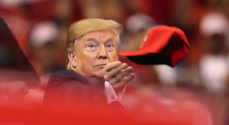 U.S. President Donald Trump tosses a hat into the crowd as he arrives to speak during a homecoming campaign rally at the BB&T Center on November 26, 2019 in Sunrise, Florida.