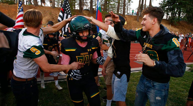 In this Aug. 23, 2019 file photo, Paradise tight end Jacob Duncan runs through a tunnel of former players during the opening ceremony of their high school football game against Williams, in Paradise, Calif.