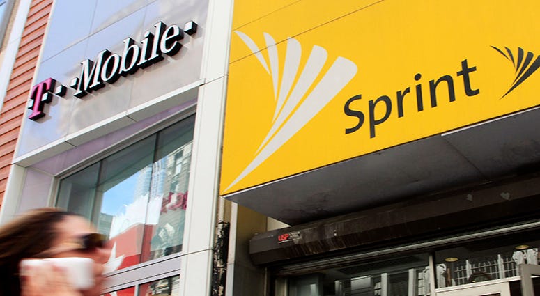 Sprint T-Mobile FILE- In this April 27, 2010 file photo, a woman using a cell phone walks past T-Mobile and Sprint stores in New York. T-Mobile and Sprint are trying again to combine in a deal that would reshape the U.S. wireless landscape, the companies announced Sunday