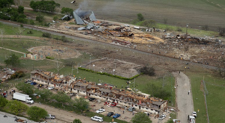 West, Texas File Photo: Search and rescue workers comb through what remains of a 50-unit apartment building (foreground) the day after an explosion at the West Fertilizer Company (background) destroyed the building April 18, 2013 in West, Texas. According to West May