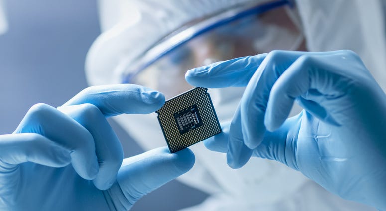Design Engineer in Sterile Coverall Holds Microchip with Gloves Design Engineer in Sterile Coverall Holds Microchip with Gloves
