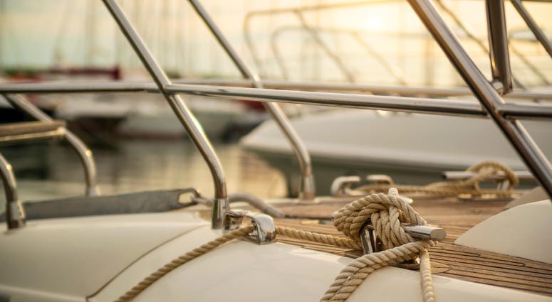 White mooring rope tied around steel anchor on boat White mooring rope tied around steel anchor on boat