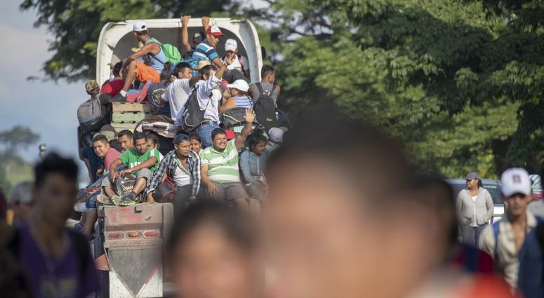 Migrant Caravan Oct 29, 2018; Mexico; The migrants are hitching rides on trucks and in pickups and cars at an immigration checkpoint as immigration officers watch.