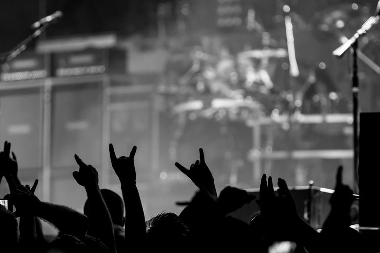 Bunch of fans happy during a concert throwing up the devil horns Bunch of fans happy during a concert throwing up the devil horns
