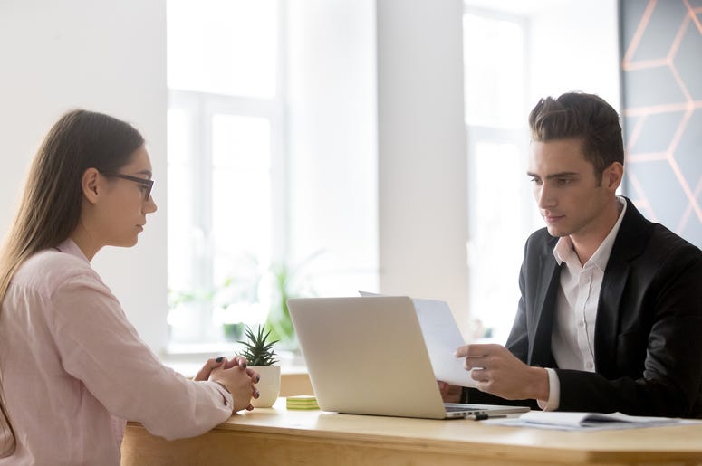 Serious hr attentively reading resume of candidate at job interv