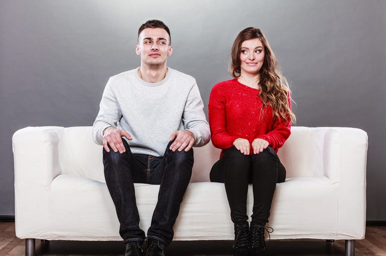 Shy woman and man sitting on sofa. First date.