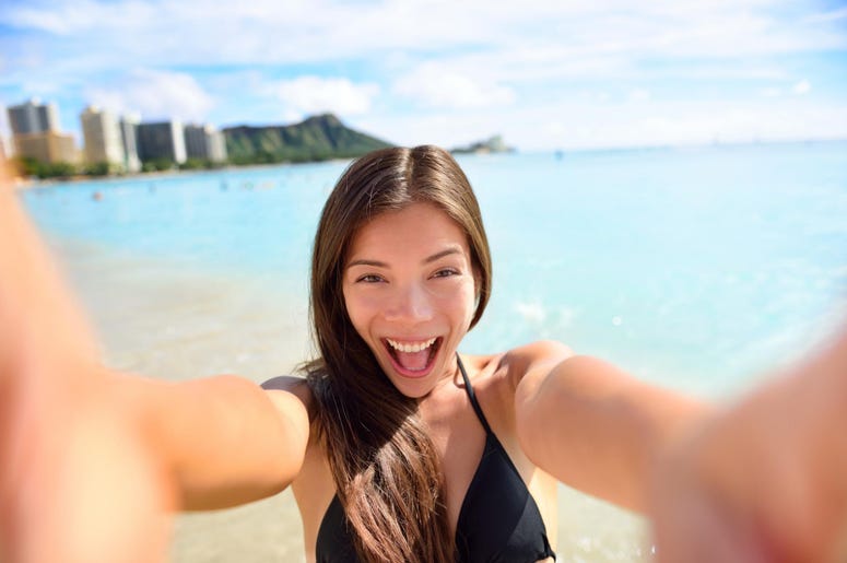 Selfie fun woman taking picture at beach vacation. Summer holiday girl happy at smartphone camera taking self-portrait on her Hawaiian travel vacations in Waikiki, Honolulu city, Oahu, Hawaii, USA.