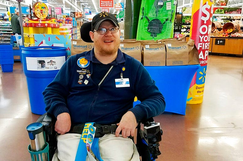 In this April 21, 2018 photo provided by Rachel Wasser, Walmart greeter John Combs works at a Walmart store in Vancouver, Wash. Combs, who has cerebral palsy, and other greeters with disabilities are threatened with job loss as Walmart transforms the gree