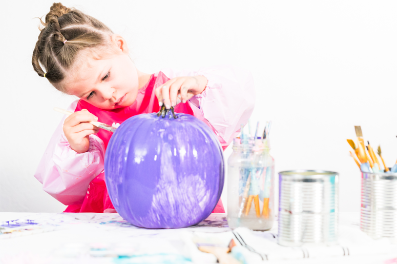Girl painting pumpkin purple