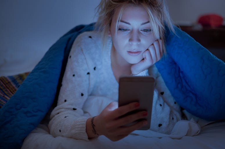 (tommaso79/ iStock/ Getty Images Plus) Girl looking at phone in bed before falling asleep