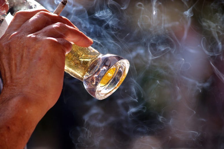 Man drinking beer and holding lit cigararette Man drinking beer and holding lit cigararette
