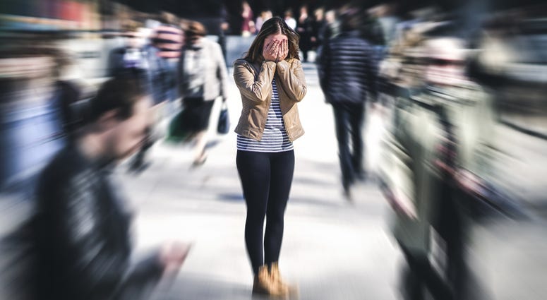 Panic attack in public place. Woman having panic disorder in city. Psychology, solitude, fear or mental health problems concept. Depressed sad person surrounded by people walking in busy street.