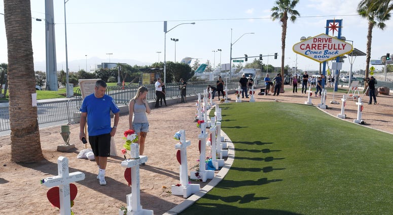Visitors look at crosses set up for shooting victims behind the Welcome to Fabulous Las Vegas sign on October 1, 2018