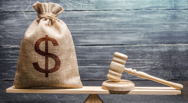 Bag of money with a dollar sign and a judge's hammer on the scales.