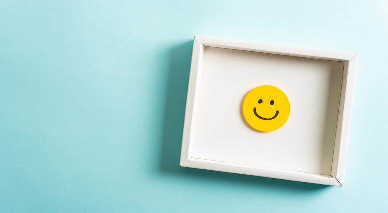 Concept of well-being, well done, feedback, employee recognition award. Happy yellow smiling emoticon face frame hanging on blue background with empty space for text.