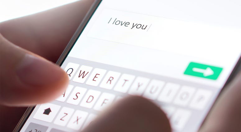 Sending I love you text message with mobile phone. Online dating, texting or catfishing concept. Romance fraud, scam or deceit with smartphone. Man writing comment. Fake profile. Internet safety