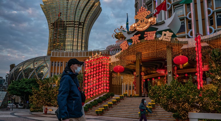 People wearing face masks walk in front of the Grand Lisboa Hotel on January 28, 2020 in Macau, China.