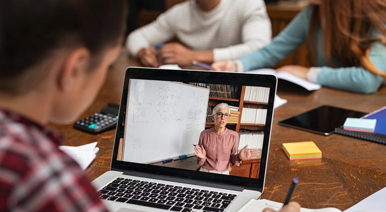 Teacher explaining lesson in video call while girl taking notes.