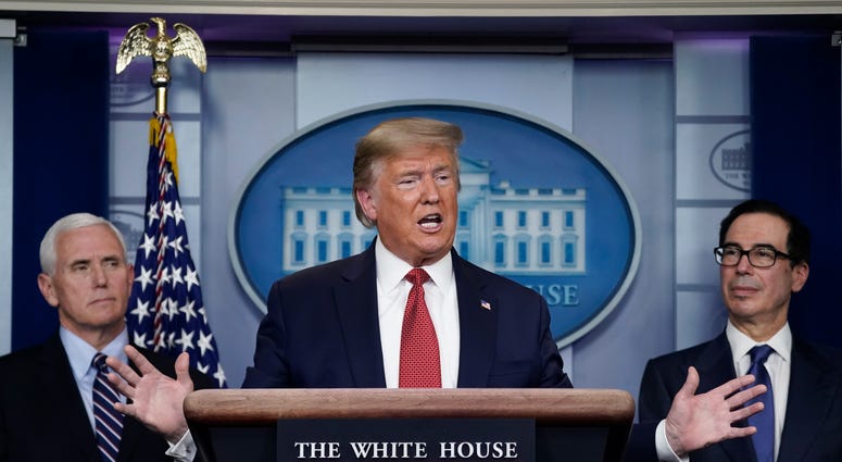 Flanked by Vice President Mike Pence (L) and Treasury Secretary Steven Mnuchin, U.S. President Donald Trump speaks during a briefing on the coronavirus pandemic, in the press briefing room of the White House on March 25, 2020