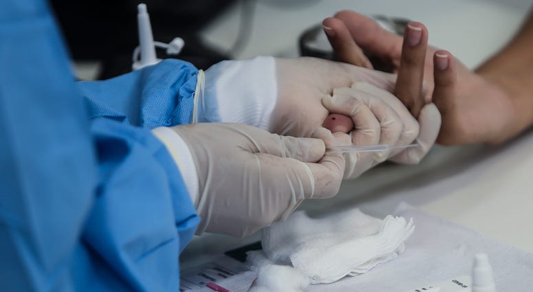 A health worker wearing a protective medical equipment extracts a blood sample from a patient's finger to make an antibody test for patients suspected of being infected with for the coronavirus (COVID-19) at the Center Health Teixeira de Freitas, on April