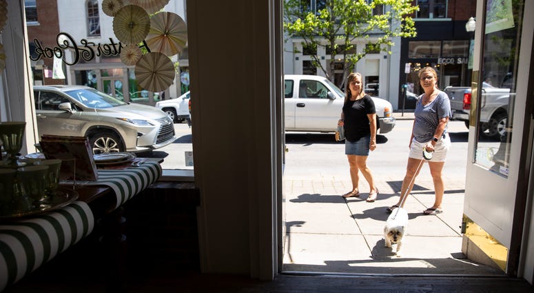 People walk between shops and restaurants that have reopened this week following loosening of non essential business restrictions on May 2, 2020 in Franklin, Tennessee