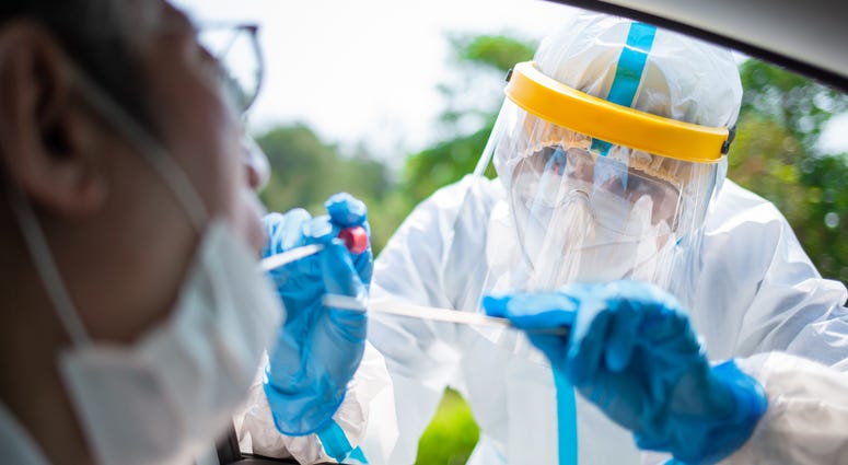 Coronavirus test - Medical worker taking a throat swab for coronavirus sample from a potentially infected elder man with the isolation gown or protective suits and surgical face masks