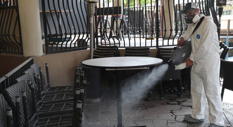 Edwin Britto, from Copax llc.) sprays a decontamination fog as he sanitizes a restaurant before it opens on May 18, 2020 in Fort Lauderdale, Florida.
