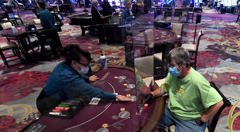 Nila Davis (L) deals cards to Becky Lewis of Texas at a blackjack table with plexiglass safety shield dividers at Excalibur Hotel & Casino after the Las Vegas Strip