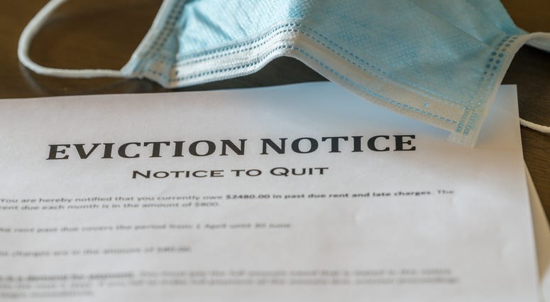 Defaulting renter with facemask receives letter giving notice of eviction from home on wooden table