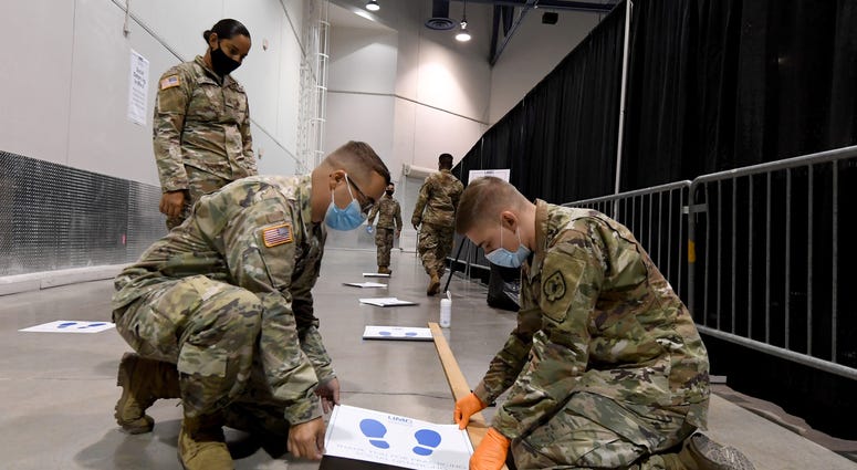 Members of the Nevada National Guard Pfc. Erika Garcia, Spc. Austin Stolpe and Pfc. Josh Wood put down social distancing decals at a new coronavirus (COVID-19) testing site inside Cashman Center on August 3, 2020