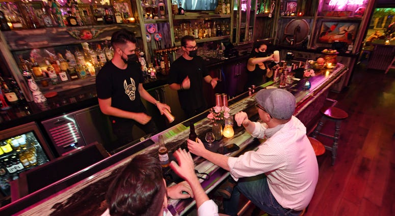 Barback Jaime Torres, bar manager Chance Bennett and bartender Brandi Sterner work behind the bar as Pete Cangelosi (L) and his friend Mike Silva, both of Louisiana, become the first patrons to sit at the bartop after it opened