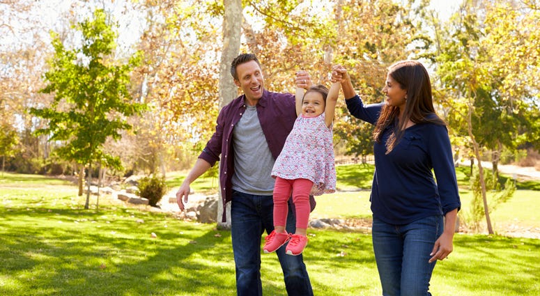 Mixed race couple lifting up their young daughter in park