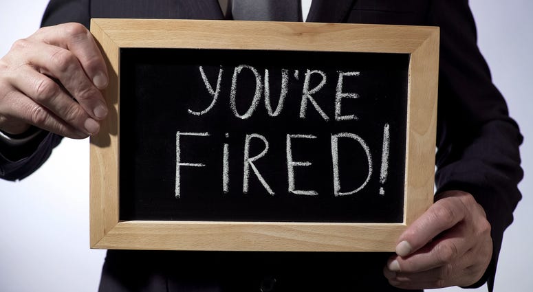 Youre fired with exclamation written on blackboard, businessman holding sign,