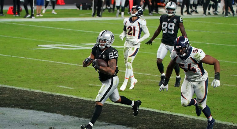 Las Vegas Raiders running back Devontae Booker (23) is pursued by Denver Broncos linebacker Josh Watson (54) on a 23-yard touchdown run in the fourth quarter at Allegiant Stadium.