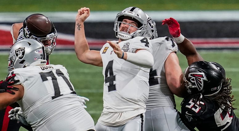Atlanta Falcons defensive tackle Jacob Tuioti-Mariner (rear left) strips the ball away from Las Vegas Raiders quarterback Derek Carr