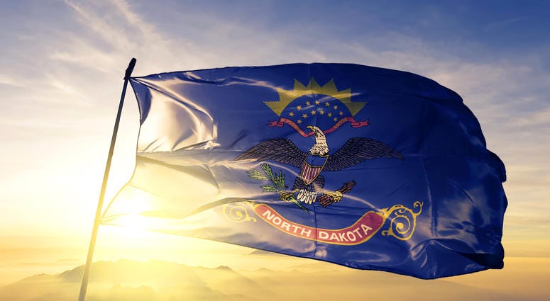 North Dakota state of United States flag on flagpole textile cloth fabric waving on the top sunrise mist fog