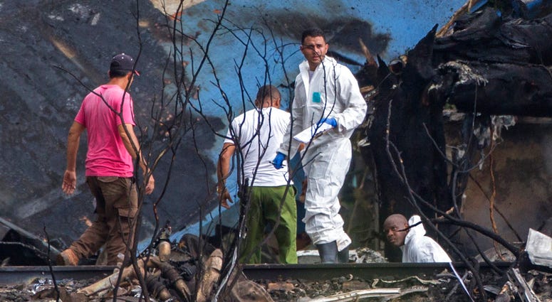 Forensic investigators and Ministry of Interior officers sift through the remains of a Boeing 737 that plummeted into a yuca field with more than 100 passengers on board, in Havana, Cuba, Friday, May 18, 2018. Cuba Plane Crash