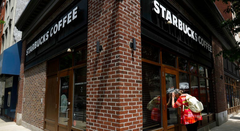 A woman peers into a closed Starbucks Coffee shop. A woman peers into a closed Starbucks Coffee shop.