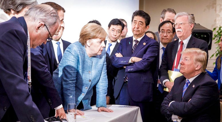 In this photo made available by the German Federal Government, German Chancellor Angela Merkel, center, speaks with U.S. President Donald Trump, seated at right, during the G7 Leaders Summit in La Malbaie, Quebec, Canada. In this photo made available by the German Federal Government, German Chancellor Angela Merkel, center, speaks with U.S. President Donald Trump, seated at right, during the G7 Leaders Summit in La Malbaie, Quebec, Canada.