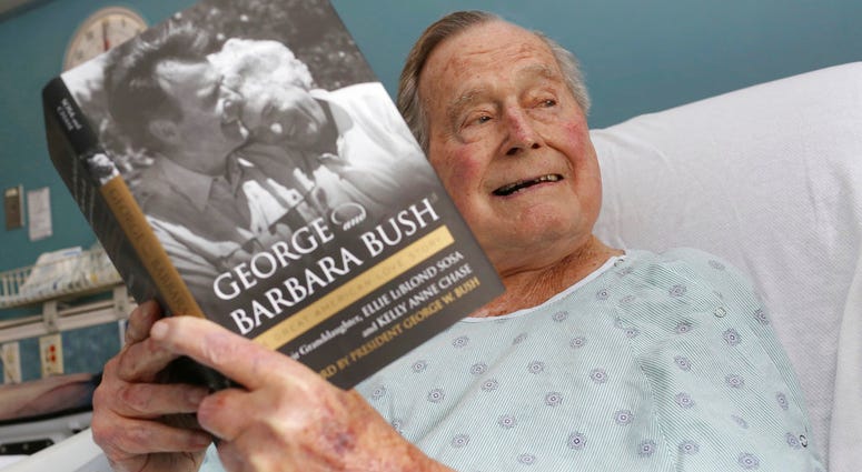 Former President George H.W. Bush sits in his hospital bed while reading a book about himself and his late wife. Former President George H.W. Bush sits in his hospital bed while reading a book about himself and his late wife.